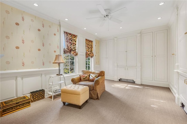 living area with carpet flooring, ceiling fan, and crown molding