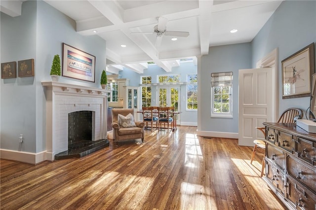 sitting room featuring coffered ceiling, ceiling fan, a fireplace, beam ceiling, and wood-type flooring