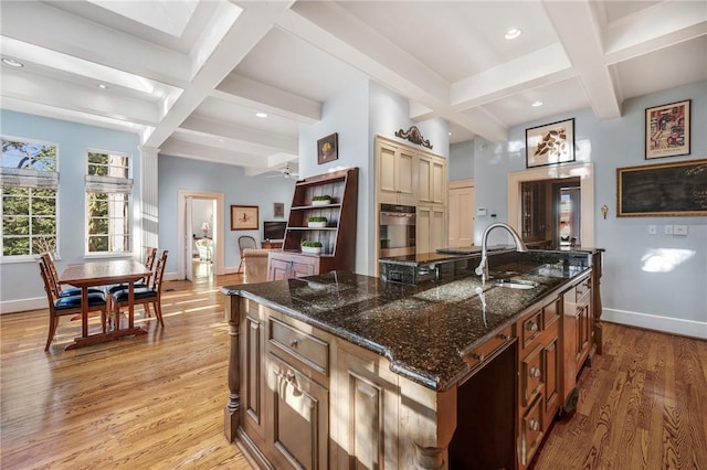 kitchen with coffered ceiling, a spacious island, sink, beamed ceiling, and light hardwood / wood-style floors