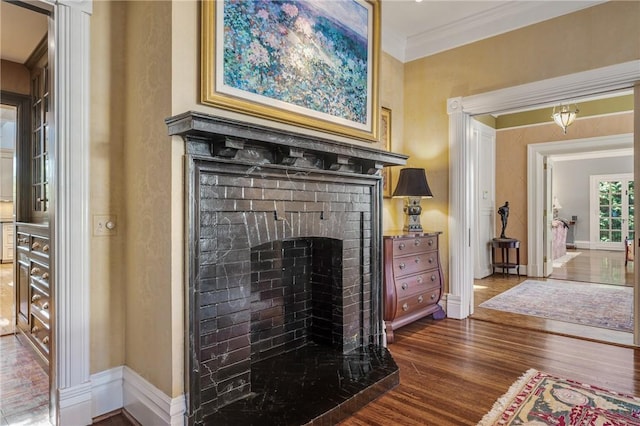 interior details featuring a fireplace, wood-type flooring, and crown molding