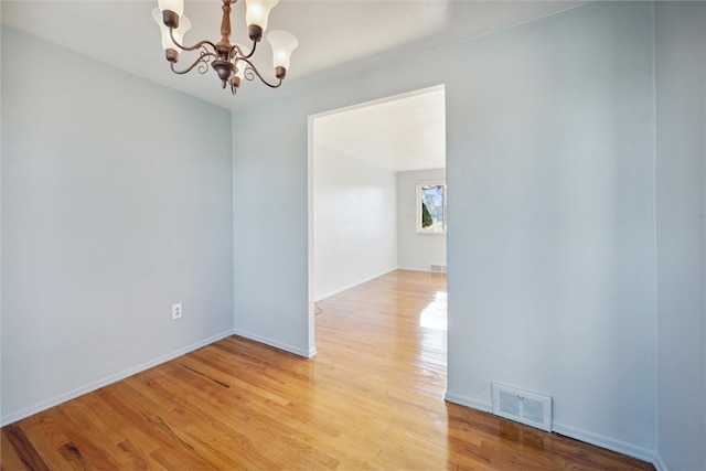 spare room with a chandelier and light hardwood / wood-style flooring