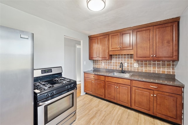 kitchen featuring tasteful backsplash, appliances with stainless steel finishes, sink, and light wood-type flooring