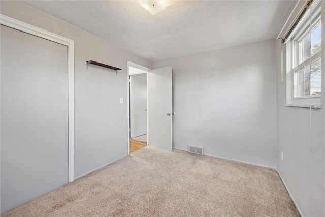 unfurnished bedroom with light colored carpet and a closet