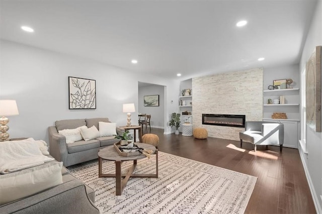 living room featuring hardwood / wood-style flooring, a fireplace, and built in shelves