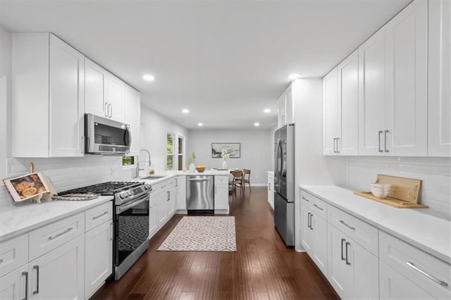 kitchen featuring kitchen peninsula, white cabinets, dark wood-type flooring, sink, and stainless steel appliances