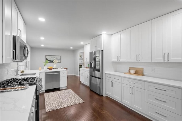 kitchen with dark wood-type flooring, stainless steel appliances, white cabinets, light stone counters, and tasteful backsplash