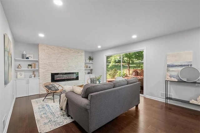 living room featuring a stone fireplace and dark hardwood / wood-style flooring