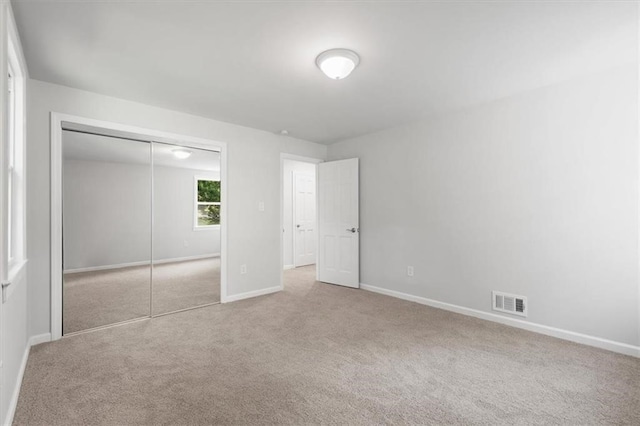 unfurnished bedroom featuring a closet and light colored carpet