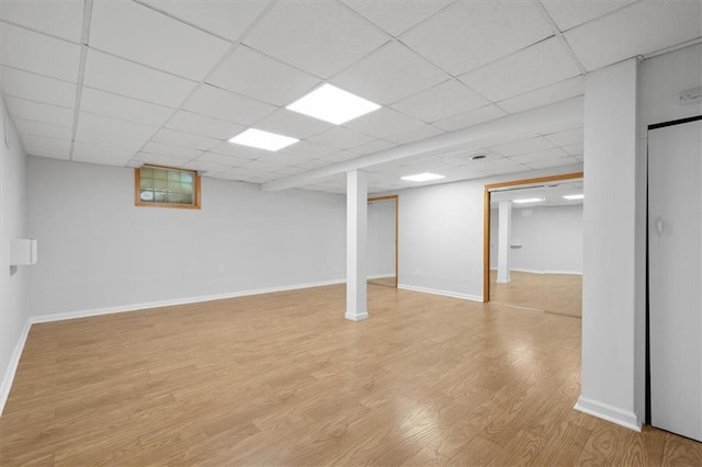 basement with a drop ceiling and light wood-type flooring