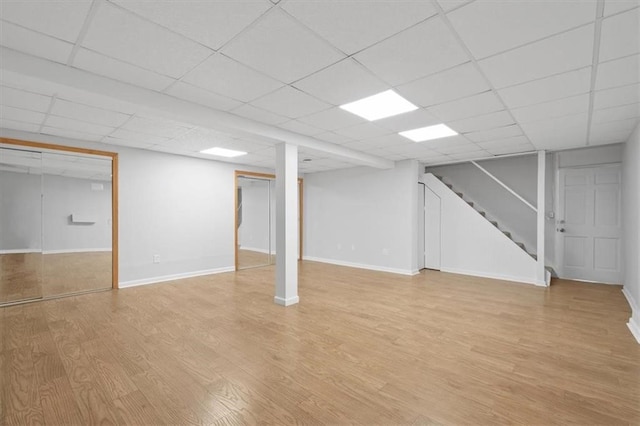 basement featuring a paneled ceiling and light hardwood / wood-style floors