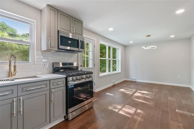 kitchen featuring gray cabinets, dark wood-type flooring, stainless steel appliances, and a healthy amount of sunlight