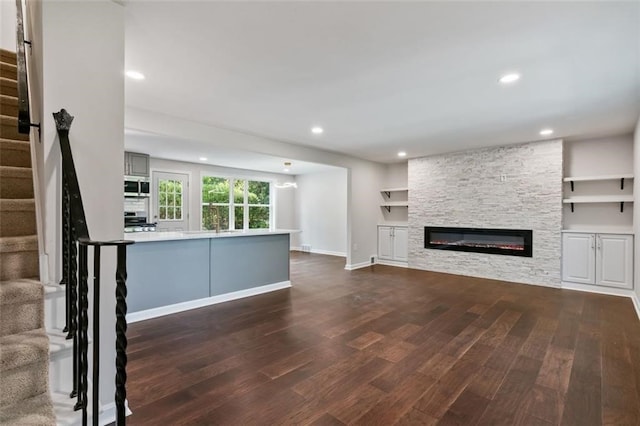 unfurnished living room with a stone fireplace and dark hardwood / wood-style floors