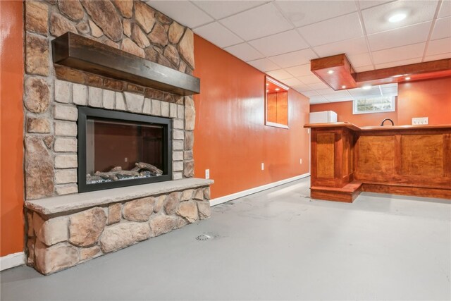 interior space featuring a drop ceiling, bar, and a fireplace