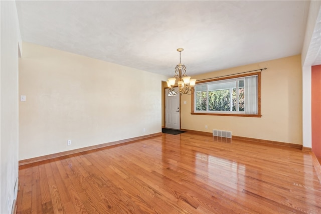 unfurnished room with a notable chandelier and light hardwood / wood-style flooring