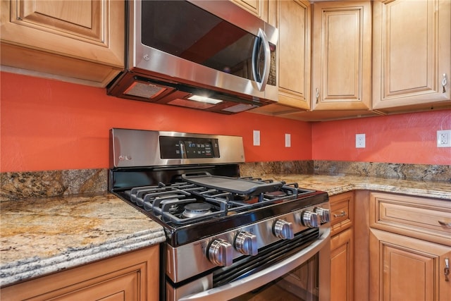 kitchen with appliances with stainless steel finishes and light stone counters