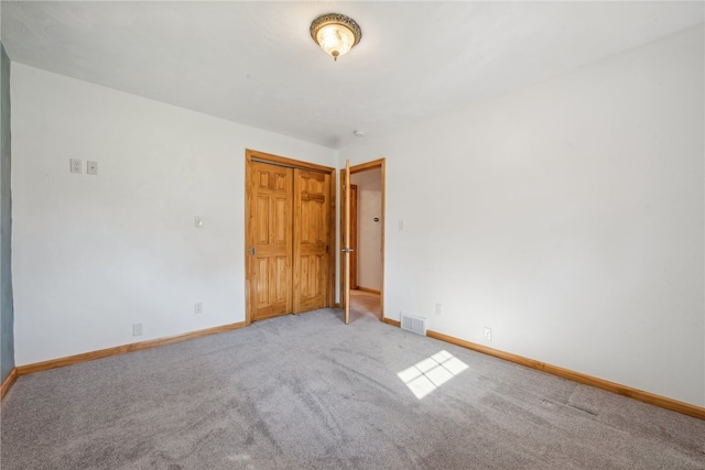 unfurnished bedroom featuring light carpet and a closet