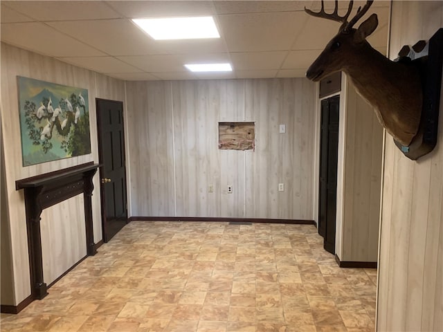 spare room featuring a paneled ceiling and wooden walls