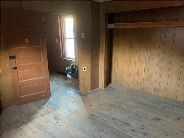 corridor with light hardwood / wood-style floors and wooden walls