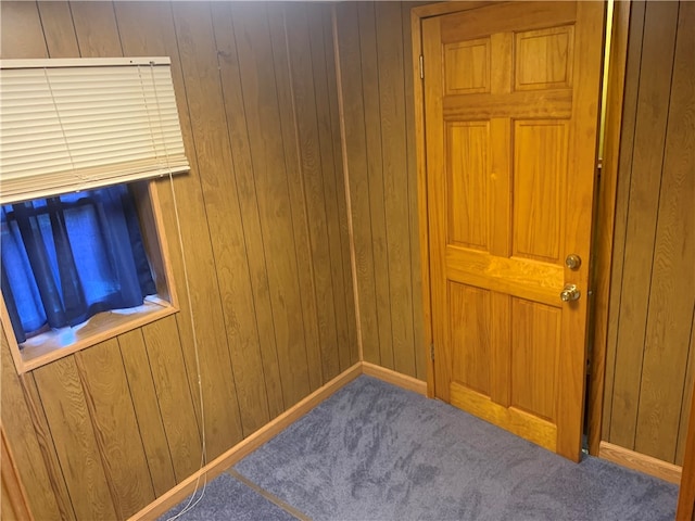 spare room featuring wooden walls and carpet