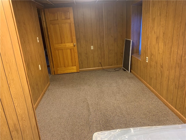 unfurnished room featuring wood walls and carpet floors