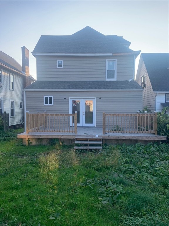 rear view of house with a wooden deck, french doors, and a lawn