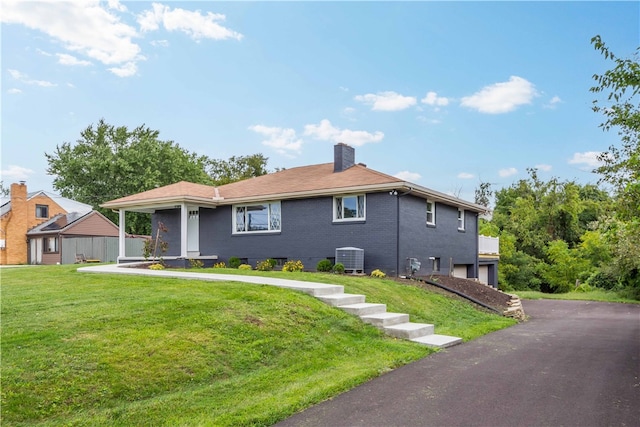 view of front of home featuring a front yard, central AC unit, and a garage