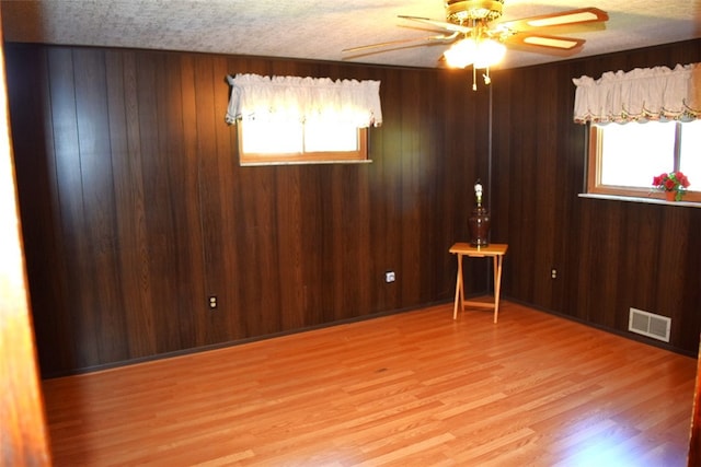 spare room with light hardwood / wood-style floors, wood walls, and plenty of natural light