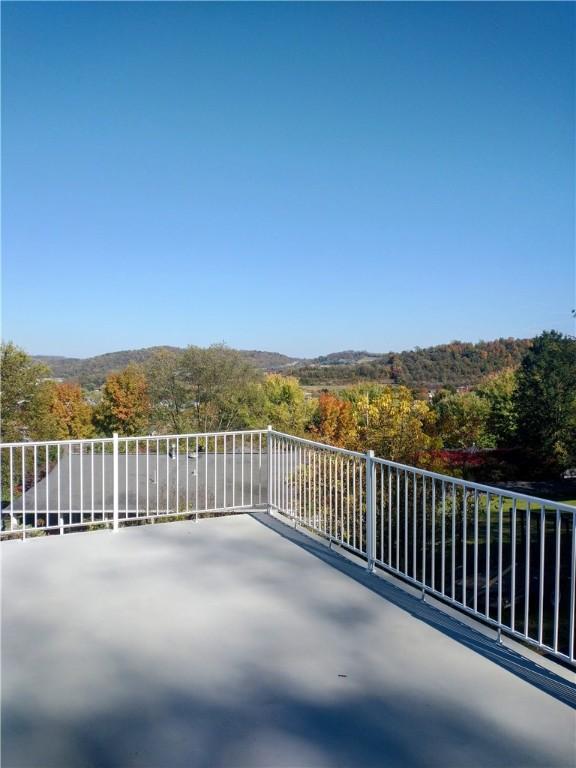 view of patio / terrace featuring a view of trees and a balcony