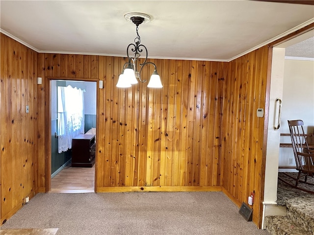 dining space with crown molding, carpet flooring, a chandelier, and wooden walls