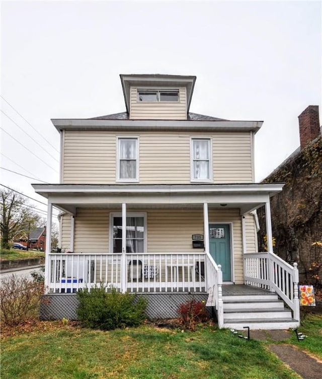 american foursquare style home featuring a porch and a front yard