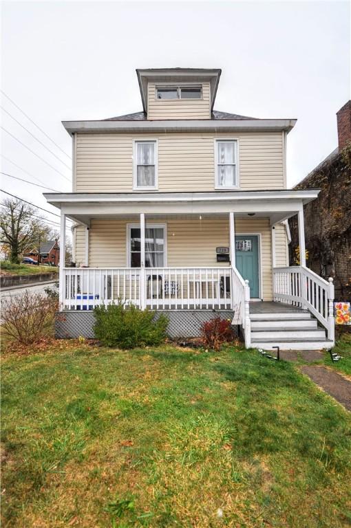 american foursquare style home with a porch and a front lawn