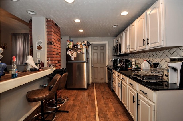 kitchen with appliances with stainless steel finishes, dark wood-style flooring, backsplash, recessed lighting, and white cabinets