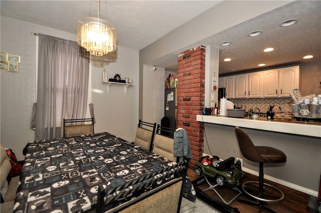 bedroom featuring light wood-type flooring, stainless steel fridge, ornate columns, and an inviting chandelier