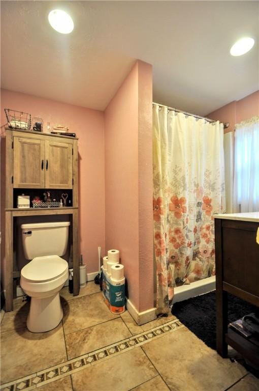 bathroom with toilet, a shower with curtain, tile patterned floors, baseboards, and vanity