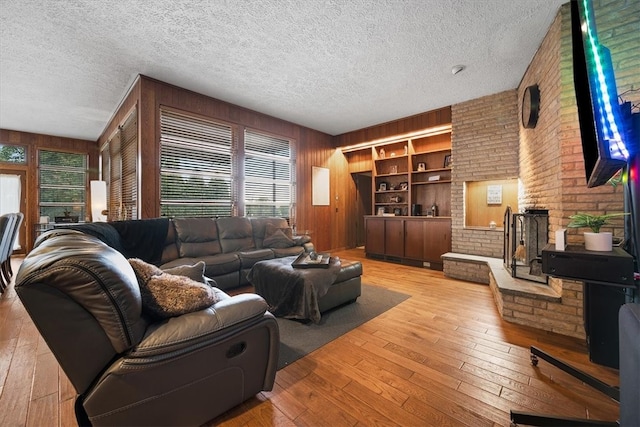 living room featuring a textured ceiling, wooden walls, and light wood-type flooring