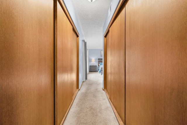 hallway featuring a textured ceiling and light colored carpet