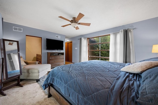 carpeted bedroom featuring ceiling fan and a textured ceiling