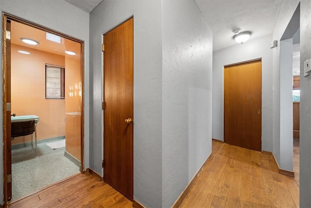 corridor featuring a textured ceiling and light hardwood / wood-style floors