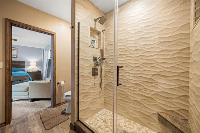 bathroom with a shower with door, hardwood / wood-style floors, and toilet