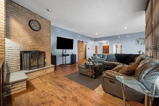 living room with hardwood / wood-style floors, a barn door, a textured ceiling, and a large fireplace