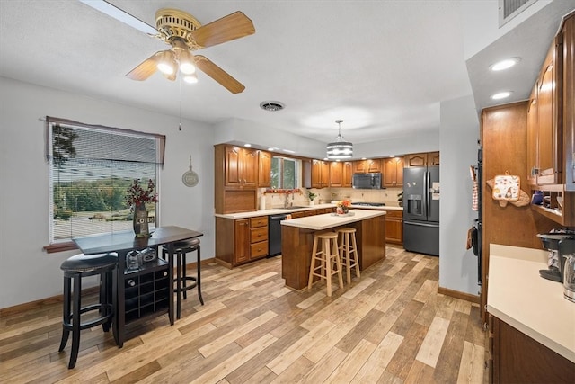 kitchen with a breakfast bar area, stainless steel appliances, sink, a center island, and light wood-type flooring