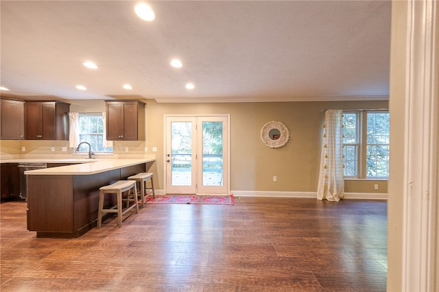 kitchen featuring a kitchen breakfast bar, dark wood-type flooring, kitchen peninsula, sink, and crown molding