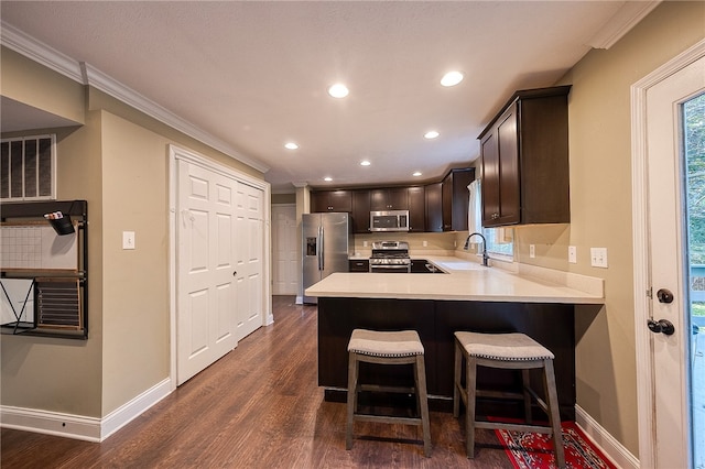 kitchen featuring kitchen peninsula, dark hardwood / wood-style flooring, appliances with stainless steel finishes, ornamental molding, and sink