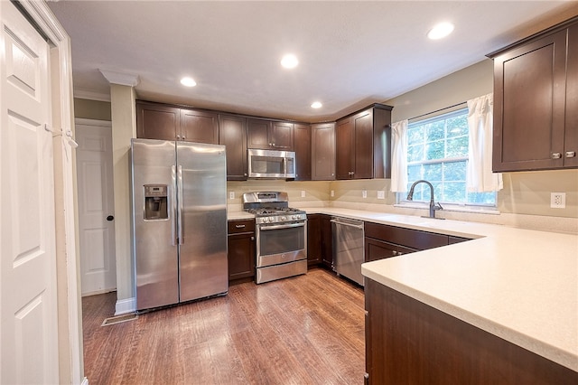 kitchen featuring sink, dark brown cabinets, appliances with stainless steel finishes, and light hardwood / wood-style flooring