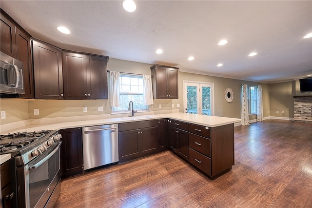 kitchen featuring dark wood-type flooring, appliances with stainless steel finishes, dark brown cabinetry, and kitchen peninsula