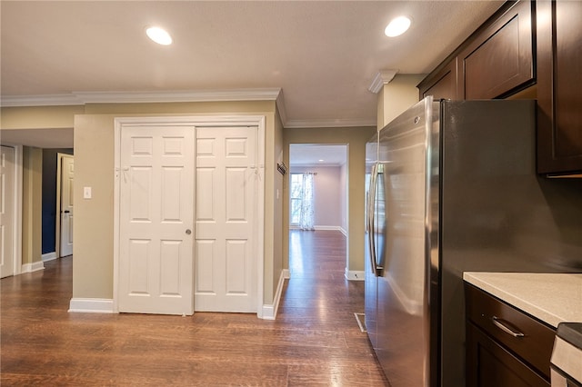 kitchen with dark hardwood / wood-style flooring, ornamental molding, dark brown cabinetry, and stainless steel refrigerator