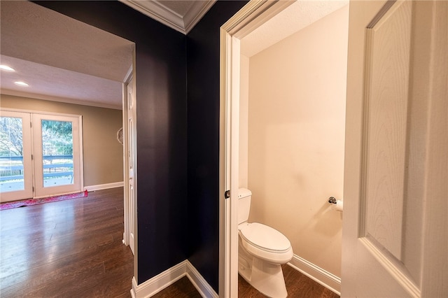 bathroom with toilet, crown molding, and hardwood / wood-style floors