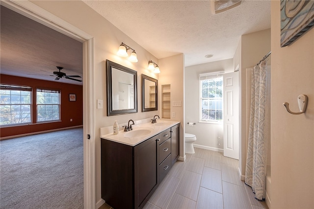 bathroom with toilet, a shower with curtain, vanity, a textured ceiling, and ceiling fan