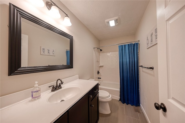 full bathroom with toilet, tile patterned flooring, shower / bath combo with shower curtain, vanity, and a textured ceiling