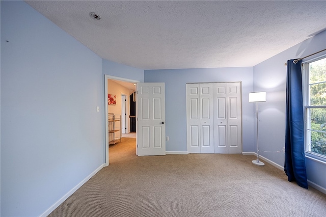 unfurnished bedroom with a textured ceiling, light colored carpet, and a closet